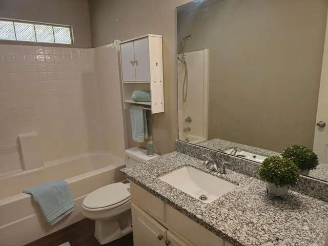 a bathroom with a granite countertop sink a toilet and shower