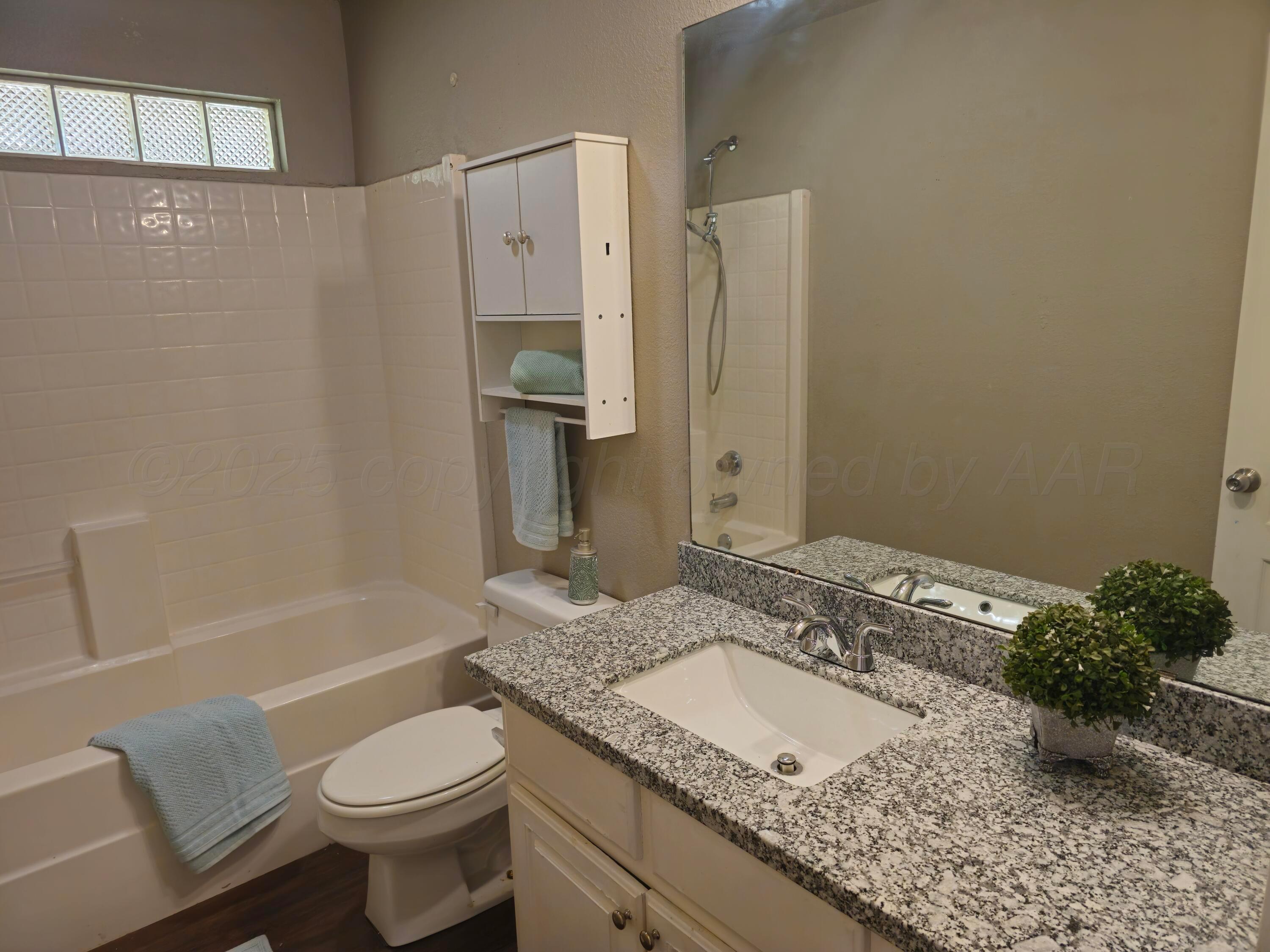 1918 75th Street Lubbock, TX 79423 - Photo 20 of 23 a bathroom with a granite countertop sink a toilet and shower