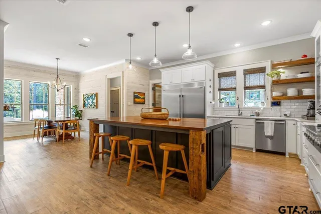 a open kitchen with stainless steel appliances granite countertop a stove a sink a oven a dining table and chairs with wooden floor