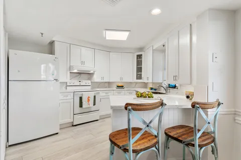 a kitchen with stainless steel appliances kitchen island a refrigerator a stove a white table and chairs