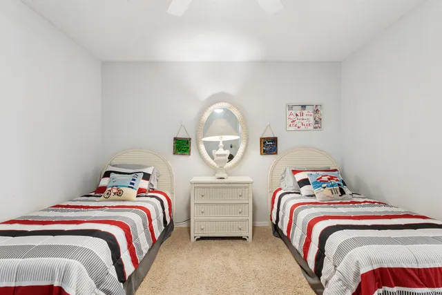 a bedroom with a bed and a lamp on dresser next to a window