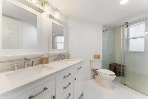 a bathroom with a double vanity sink toilet and a mirror