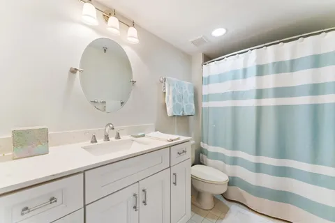 a bathroom with a sink a toilet a mirror and shower curtain