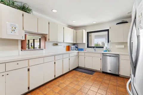 a kitchen with white cabinets a sink stove and refrigerator