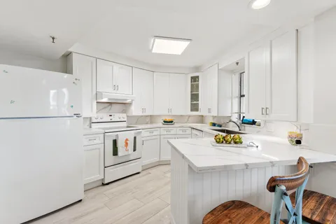 a kitchen with a sink white cabinets and white appliances