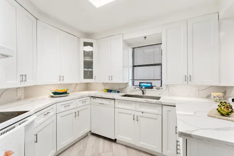 a kitchen with a sink dishwasher and white cabinets
