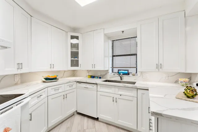 a kitchen with a sink dishwasher and white cabinets