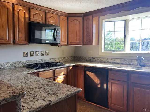 a kitchen with granite countertop wooden cabinets a stove top oven a sink and dishwasher