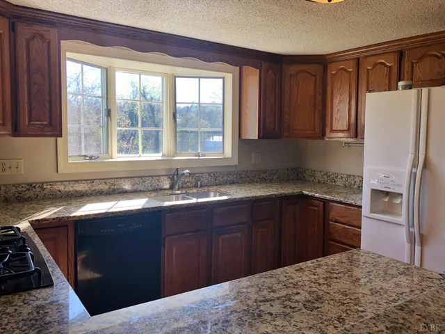 a kitchen with granite countertop a sink stove and refrigerator