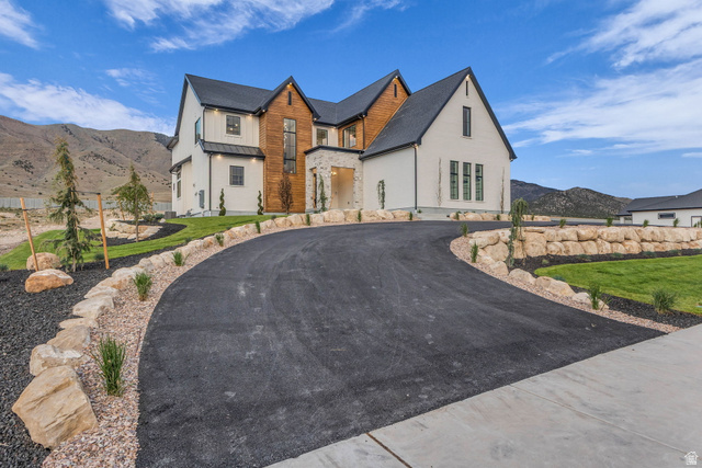 2828 Jojo Road Eagle Mountain, UT 84005 - Photo 3 of 63 Contemporary exterior featuring white siding, dark gabled rooflines, and a wood-paneled accent wall