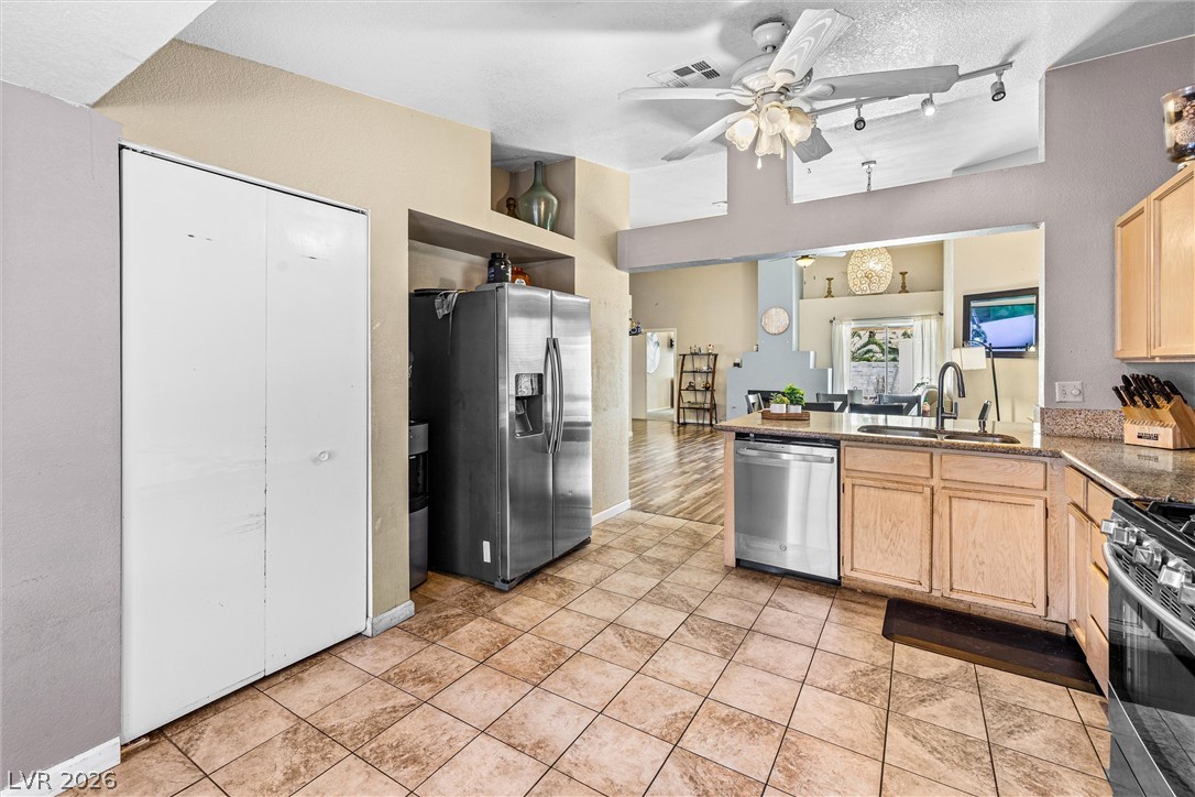 1624 Palmae Way Las Vegas, NV 89128 - Photo 6 of 18 This functional kitchen features warm wood cabinetry, a practical layout, and a view into the adjacent living areas.