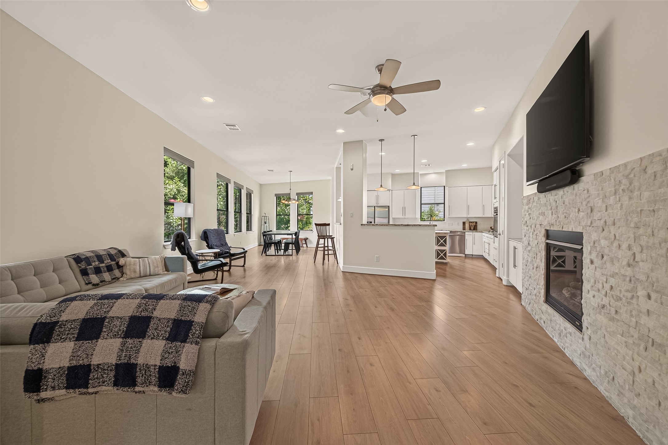 1767 Michigan Street Houston, TX 77006 - Photo 5 of 33 This open-concept living area features a modern kitchen with pendant lighting. The space is brightened by large windows and light wood flooring, creating a welcoming and airy atmosphere.