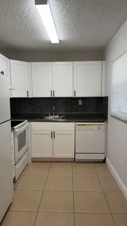 a white kitchen with granite countertop white cabinets