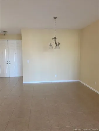 a view of an empty room and a chandelier fan