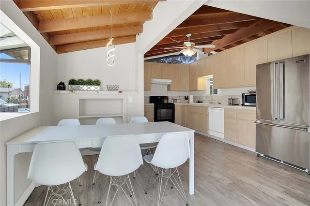 a kitchen with stainless steel appliances granite countertop a stove a refrigerator a dining table and chairs with wooden floor