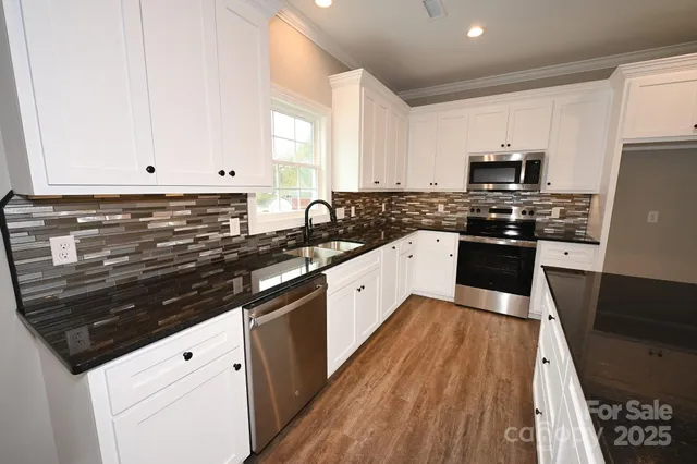 a large white kitchen with stainless steel appliances granite countertop a stove a sink dishwasher and a refrigerator