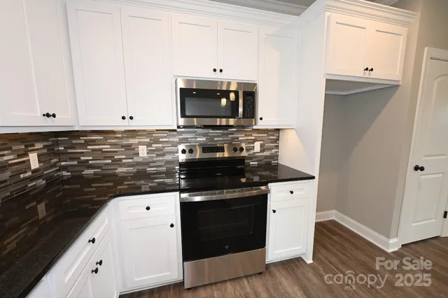 a kitchen with granite countertop white cabinets and black appliances