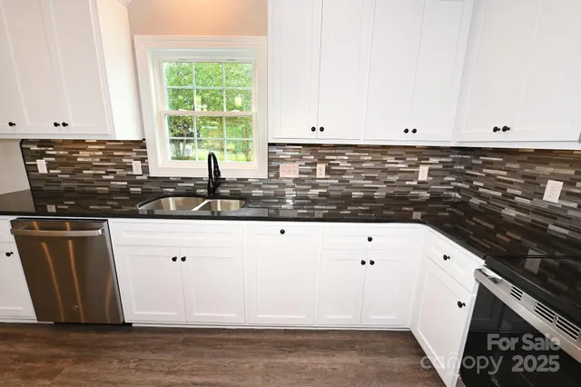 a kitchen with granite countertop white cabinets and window