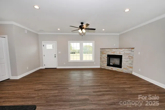 a view of empty room with wooden floor fireplace and a window