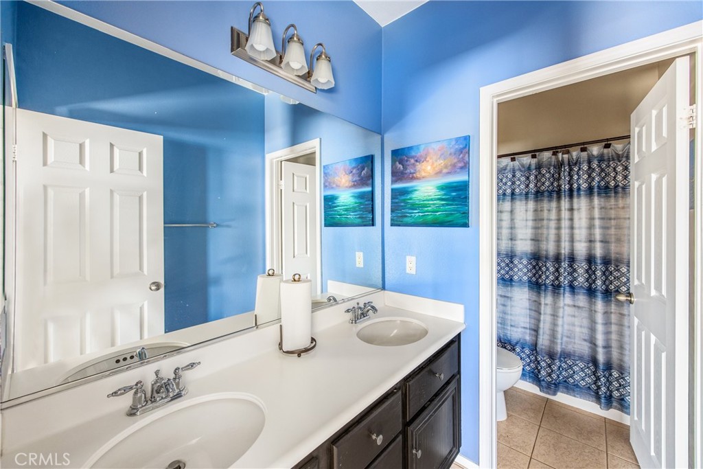 18936 Malkoha Street Perris, CA 92570 - Photo 34 of 70 a bathroom with a granite countertop sink and a mirror