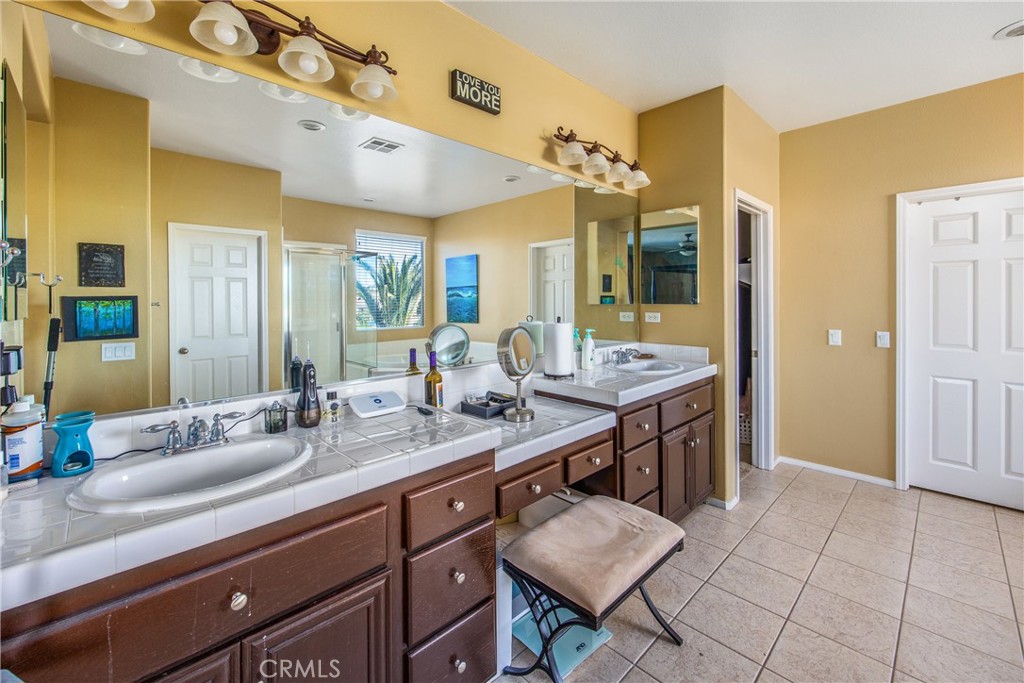 18936 Malkoha Street Perris, CA 92570 - Photo 46 of 70 a spacious bathroom with a granite countertop sink a mirror and a shower