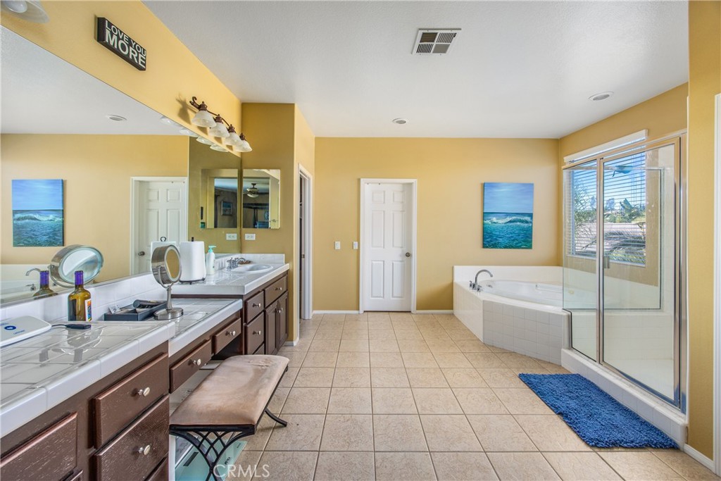 18936 Malkoha Street Perris, CA 92570 - Photo 48 of 70 a spacious bathroom with a granite countertop sink a mirror a bathtub and next to a window