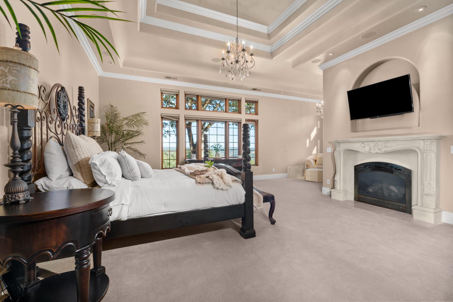 1100 Cold Springs Road Placerville, CA 95667 - Photo 32 of 97 Primary Bedroom - Spacious bedroom featuring a tray ceiling, ornate chandelier, large windows, a decorative fireplace with a built-in television niche, and neutral wall tones