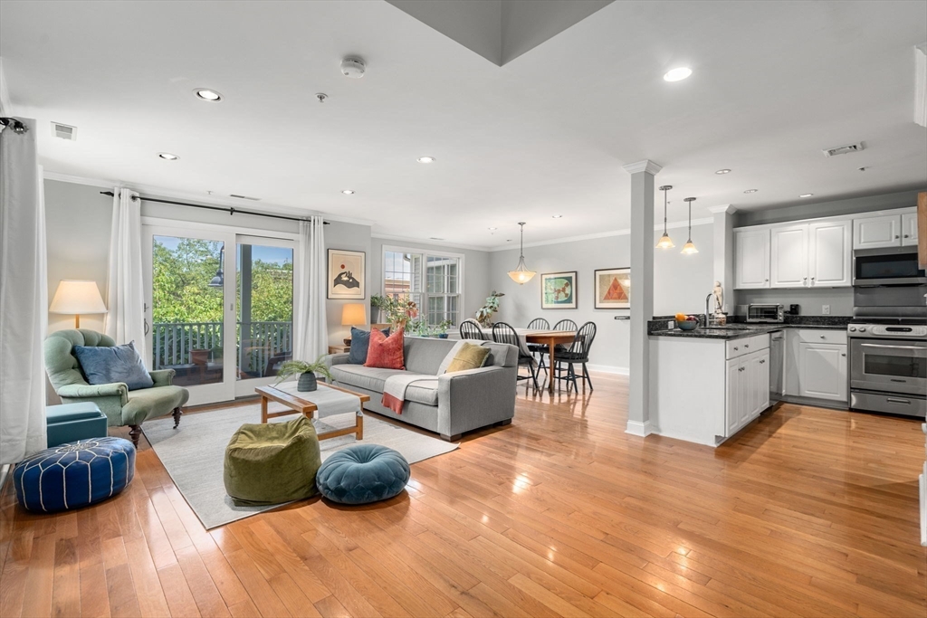 104 Harvard Street, Unit 6 Brookline, MA 02446 - Photo 2 of 18 a living room with furniture and kitchen view with wooden floor