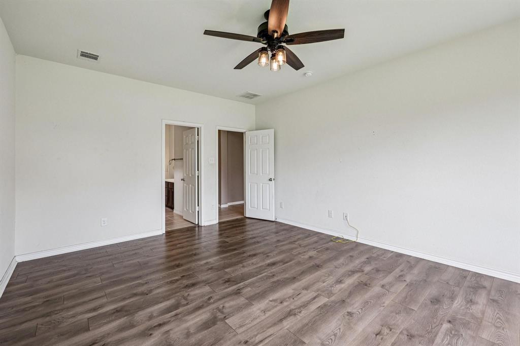 2712 Ryder Lane Aubrey, TX 76227 - Photo 9 of 26 a view of an empty room with window a ceiling fan and wooden floor