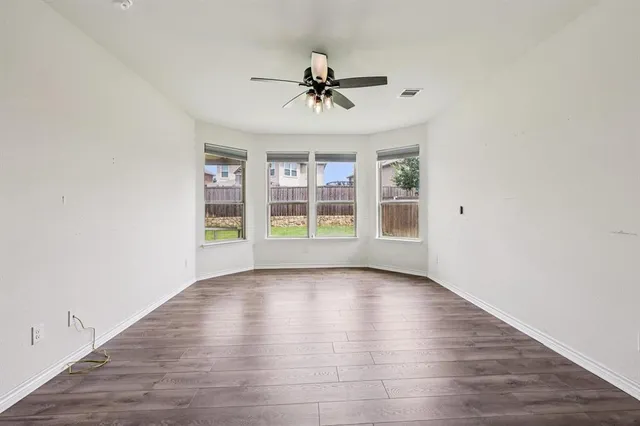 an empty room with wooden floor chandelier and windows