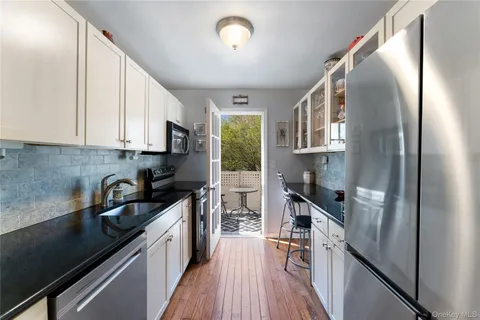 a kitchen with granite countertop a refrigerator a sink dishwasher a stove and white countertops with wooden floor