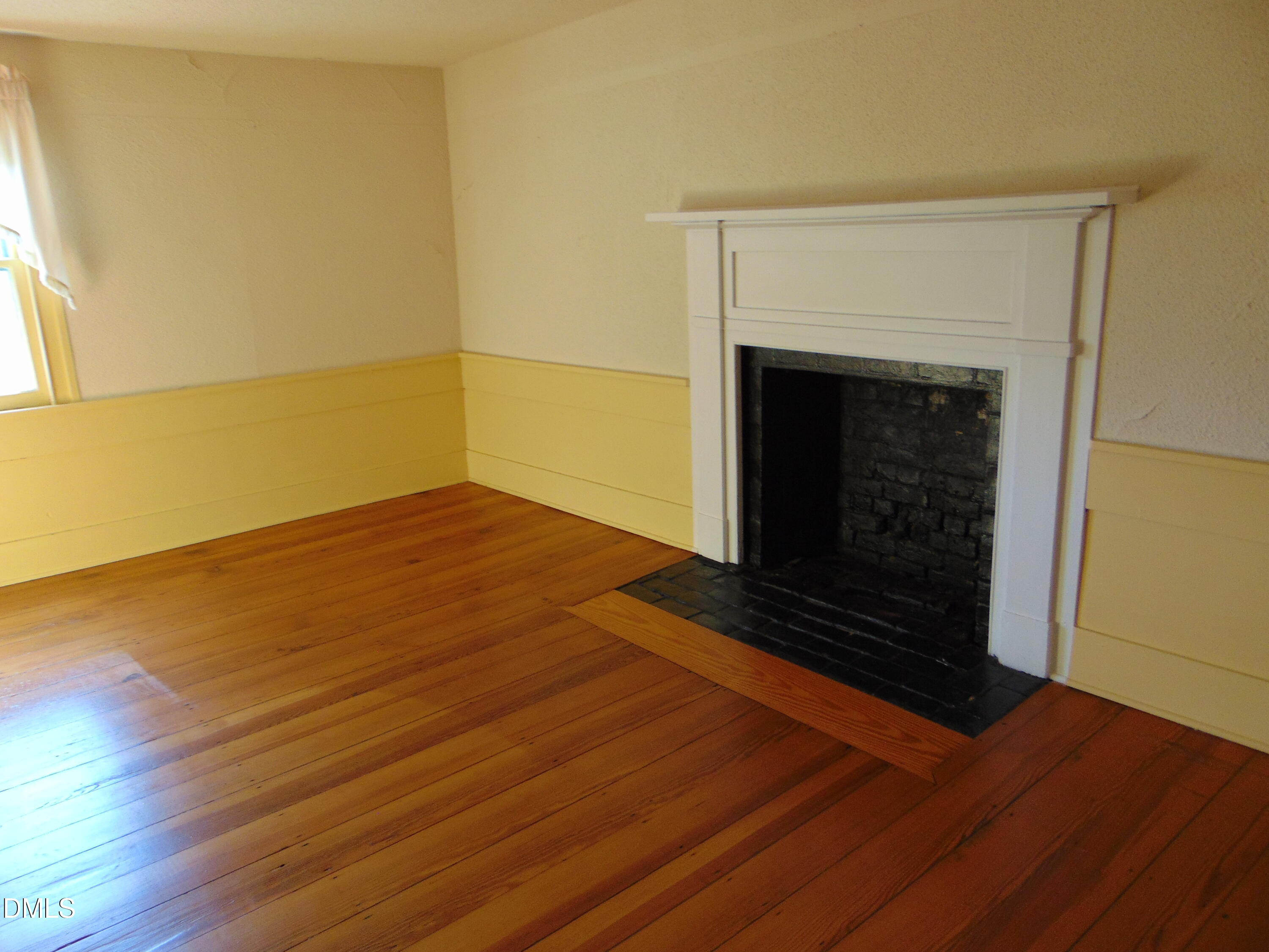 4067 Chewning Road Oxford, NC 27565 - Photo 71 of 82 a view of an empty room with wooden floor a fireplace and a window