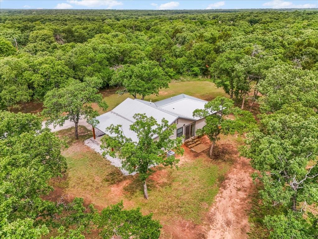 304 County Road 340 Ranger, TX 76470 - Photo 14 of 30 Modern home with a light-colored metal roof and a spacious, verdant treed lot