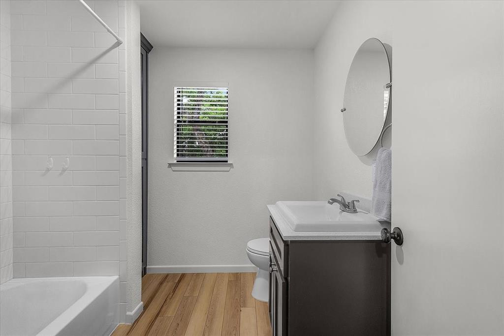 304 County Road 340 Ranger, TX 76470 - Photo 10 of 30 Bathroom featuring a single vanity with dark cabinetry, integrated sink, and round wall-mounted mirror