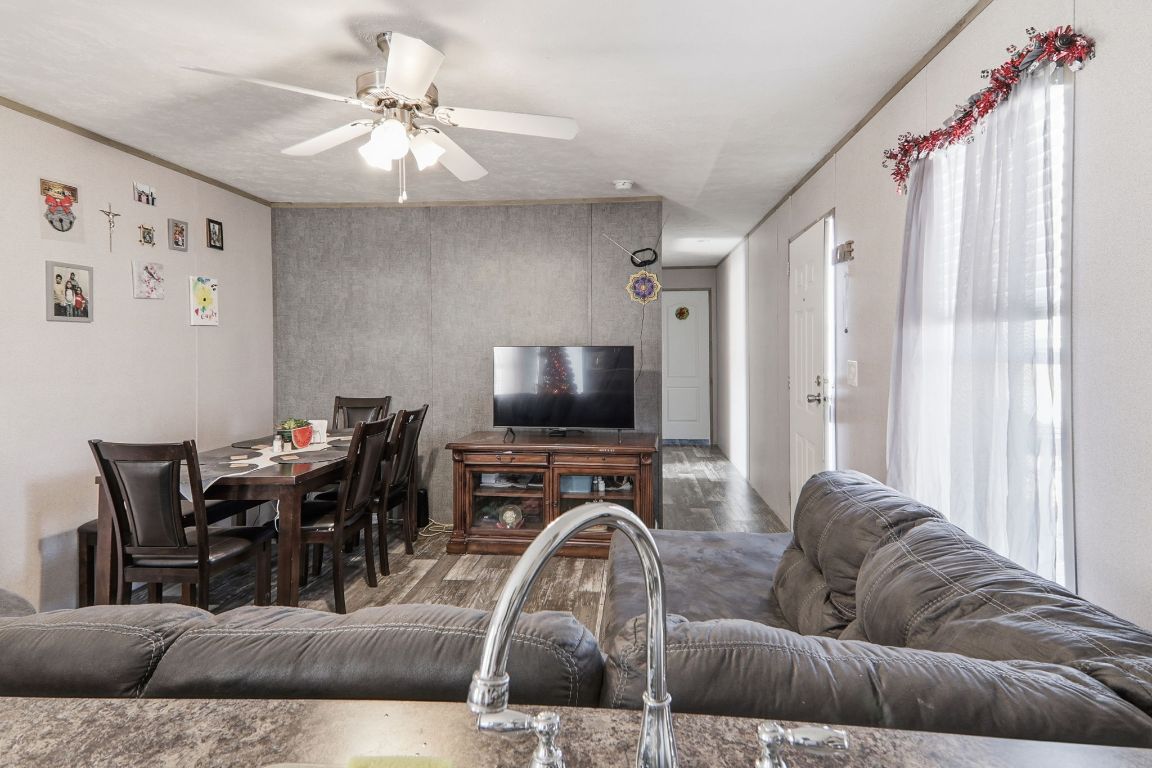 1130 Rustler Pass Kyle, TX 78640 - Photo 5 of 21 Living room featuring an accent wall, a ceiling fan, ornamental molding, and wood finished floors