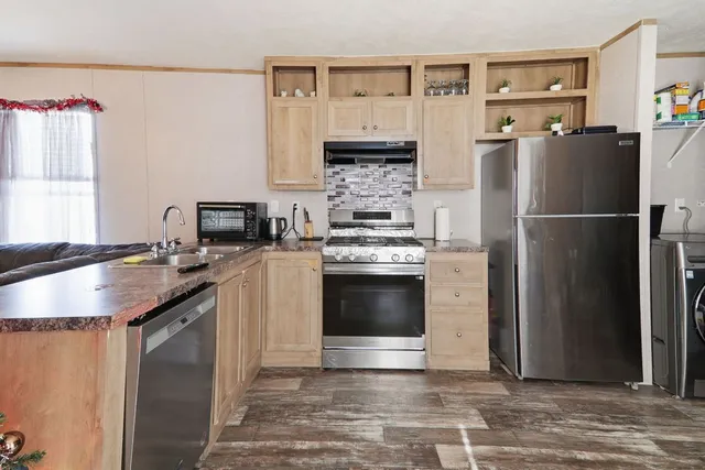 a kitchen with stainless steel appliances granite countertop a refrigerator a stove and a sink