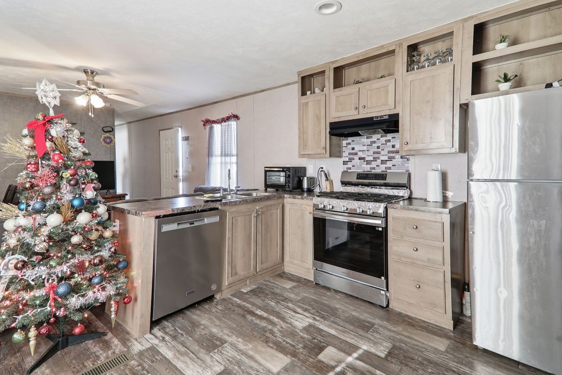 1130 Rustler Pass Kyle, TX 78640 - Photo 7 of 21 Kitchen featuring stainless steel appliances, light brown cabinets, a peninsula, under cabinet range hood, and crown molding