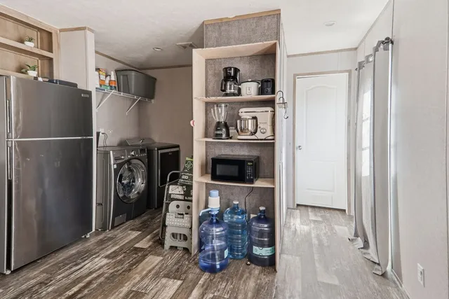 a kitchen with stainless steel appliances a refrigerator and a wooden floor