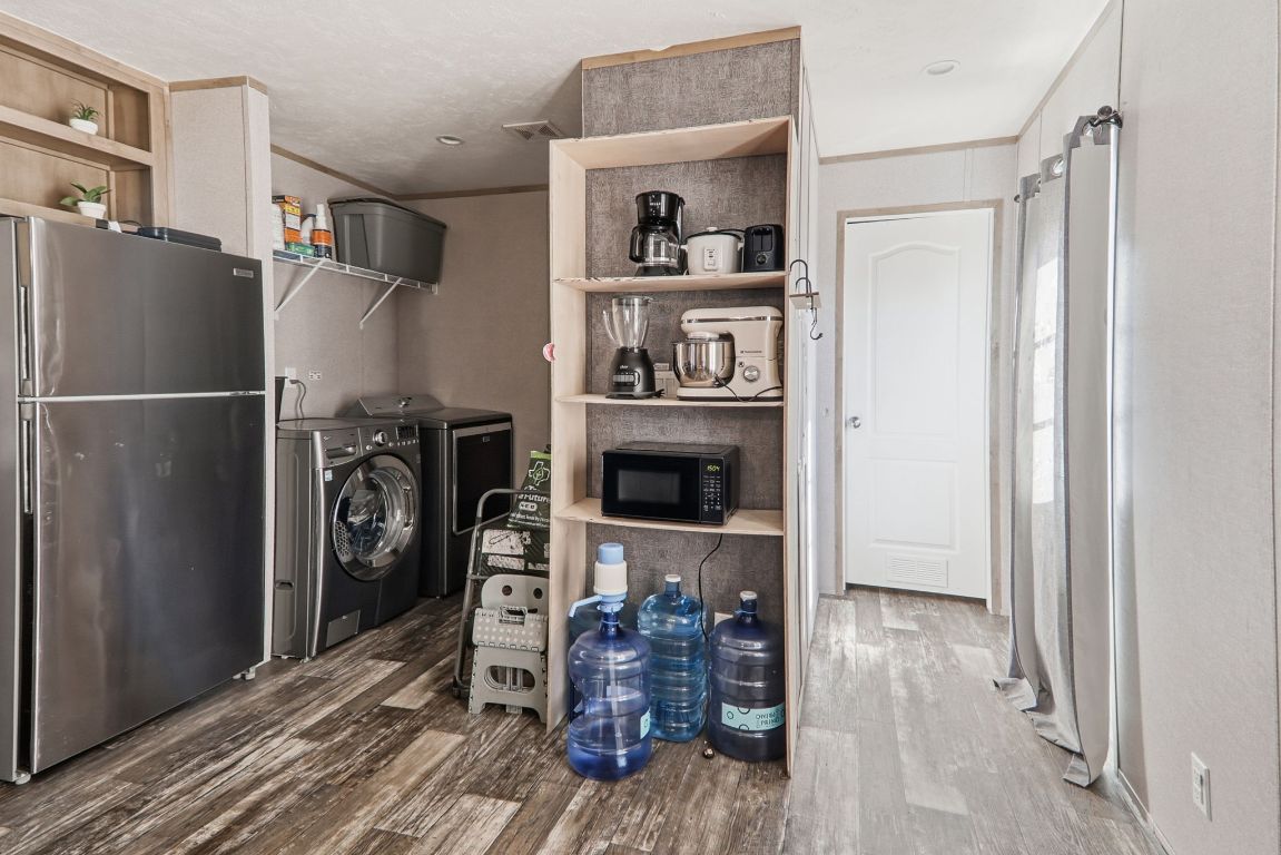 1130 Rustler Pass Kyle, TX 78640 - Photo 8 of 21 Laundry room featuring dark wood-type flooring, ornamental molding, and separate washer and dryer