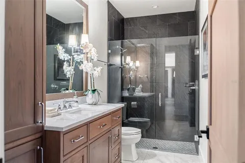 a bathroom with a granite countertop sink toilet a mirror and shower