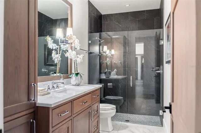 a bathroom with a granite countertop sink toilet a mirror and shower