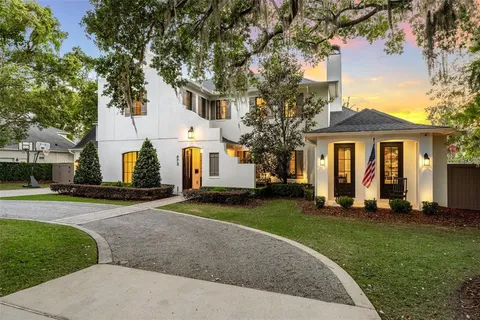 a view of a white house with a yard and large tree