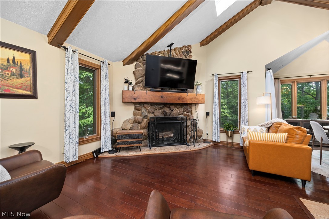 7587 Lewis Road Olmsted Falls, OH 44138 - Photo 8 of 50 Vaulted ceiling with exposed wood beams, stone fireplace with a substantial wood mantel, dark wood-finish flooring, and multiple windows