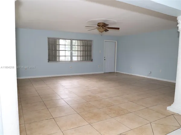 a view of empty room with kitchen and window