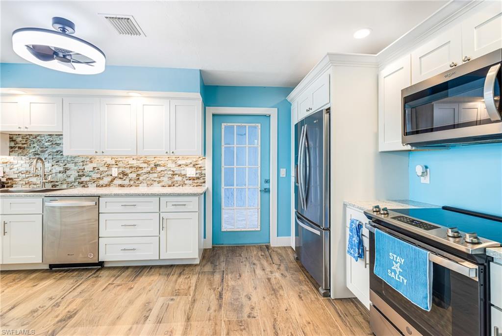 4817-4819 Gary Road Bonita Springs, FL 34134 - Photo 11 of 48 a kitchen with white cabinets and stainless steel appliances