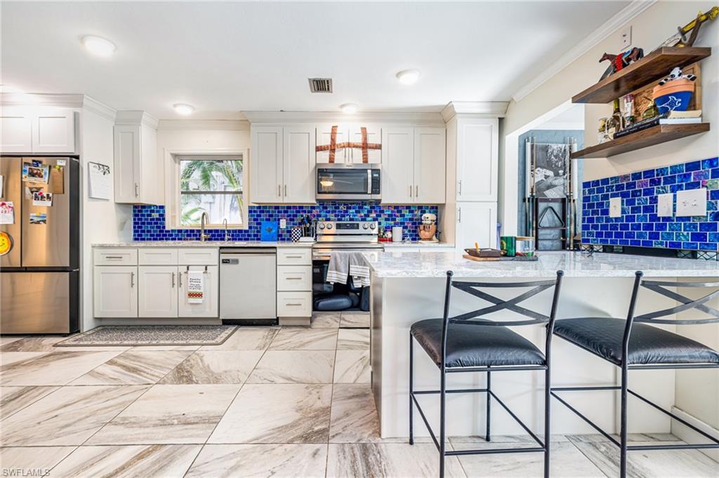 4817-4819 Gary Road Bonita Springs, FL 34134 - Photo 35 of 48 a kitchen with stainless steel appliances kitchen island granite countertop a refrigerator a stove a sink dishwasher and white cabinets with wooden floor