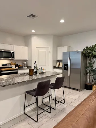 a kitchen with stainless steel appliances kitchen island granite countertop a refrigerator a stove a sink a dining table and chairs