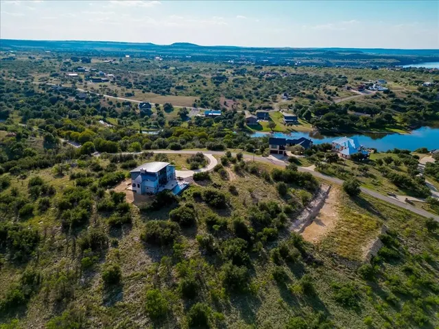 an aerial view of residential houses with outdoor space and trees