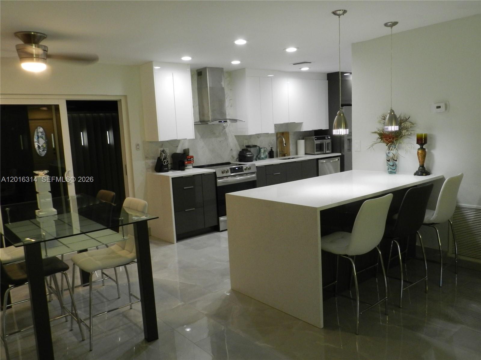 305 Northwest 42nd Street Boca Raton, FL 33431 - Photo 20 of 31 a kitchen with stainless steel appliances granite countertop table chairs sink and stove