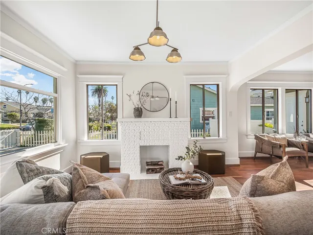 a living room with furniture a fireplace a large window and a large mirror